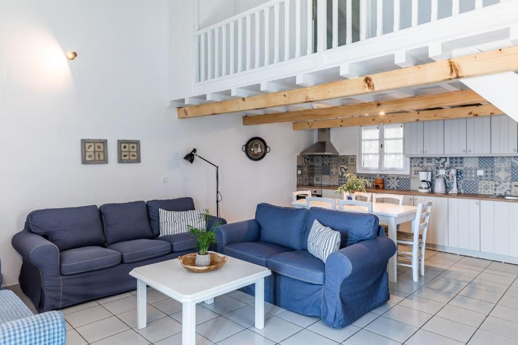 a living room with blue couches and a kitchen at Milia Beach Apartments in Paralia Milia