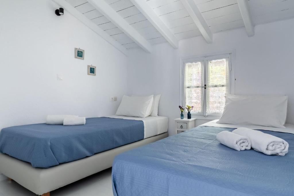 two beds in a white room with blue sheets at Milia Beach Apartments in Paralia Milia