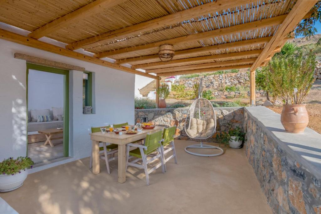 un patio con mesa y sillas bajo un techo de madera en Elia Traditional suites en Astipalea