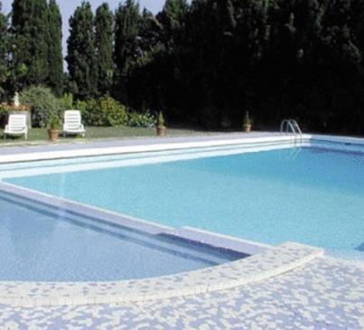 una gran piscina azul con 2 sillas y árboles en Le Domaine Du Chapitre, en Carcassonne