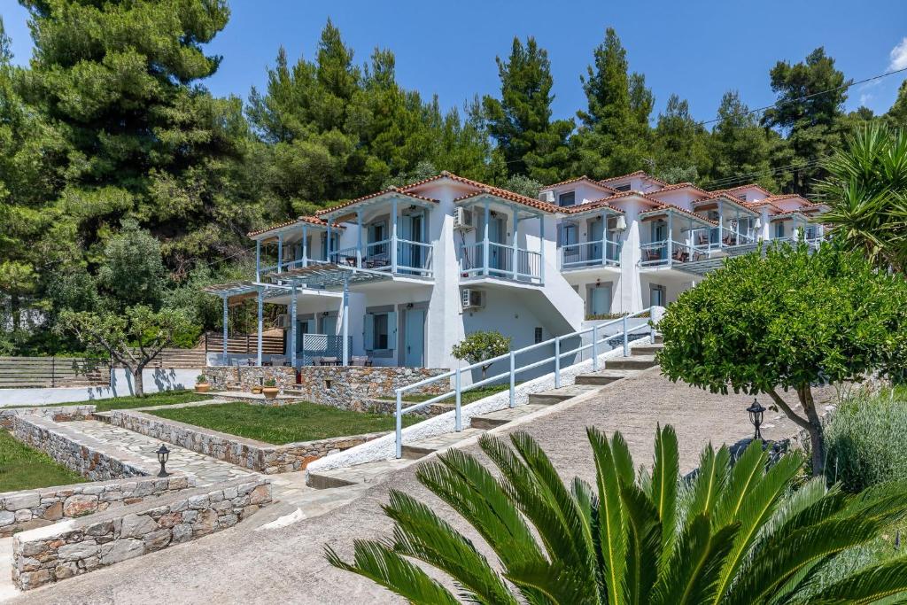 a large white house with trees in the background at Milia Beach Apartments in Paralia Milia