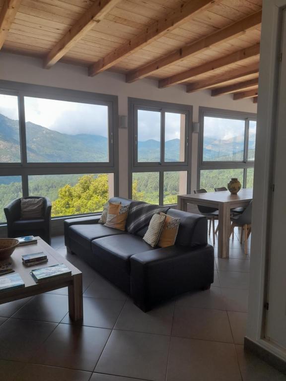 ein Wohnzimmer mit einer Couch und einem Tisch und Fenstern in der Unterkunft Chambres d'Hôtes Villa Cardellini in Aullène