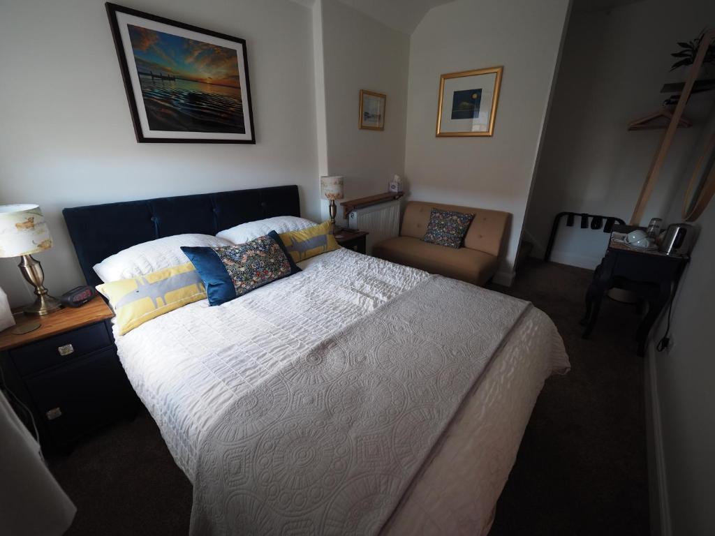 a bedroom with a large bed and a chair at Cowrie Guest House in Berwick-Upon-Tweed