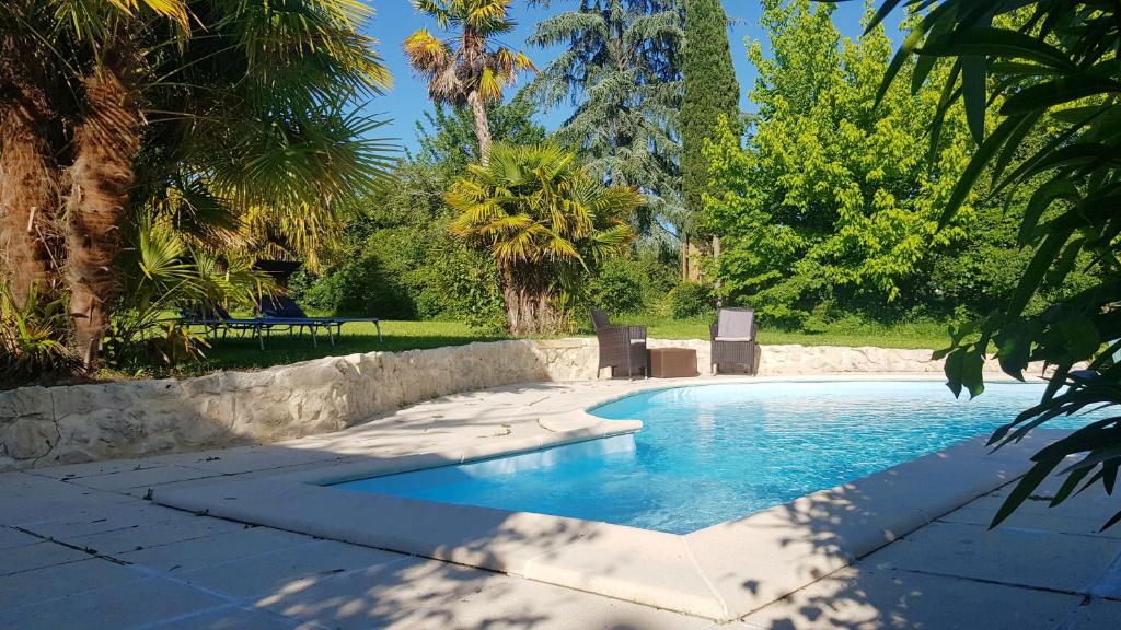 a swimming pool in a yard with palm trees at Villa Les Roses -8 pers- Piscine chauffée & cuisine d'été en Gascogne in Mézin