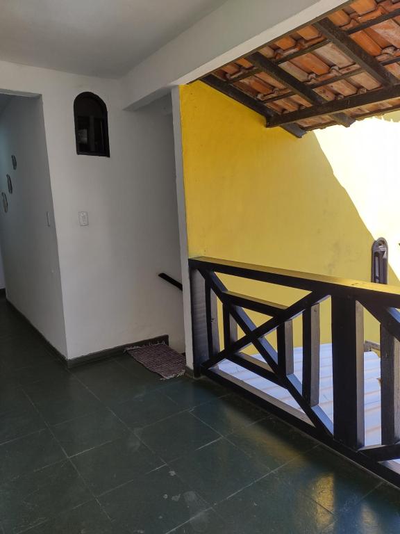 Habitación con pared amarilla y barandilla de madera. en Suites Mar Azul Prainha, en Arraial do Cabo
