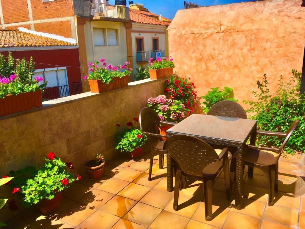 eine Terrasse mit einem Tisch, Stühlen und Blumen in der Unterkunft Casa 4Estacions Palamós 3a linia Port Marina-Camí de Ronda - pàrquing in Palamós