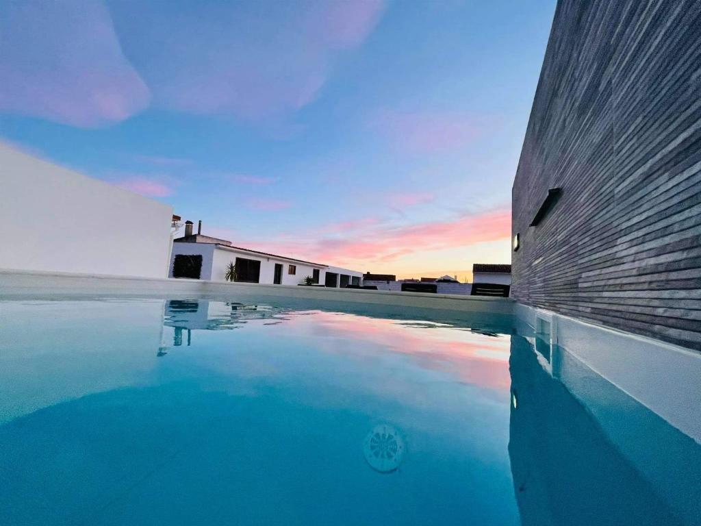 uma piscina de água junto a um edifício com o pôr do sol em Soares Village II em Amoreira