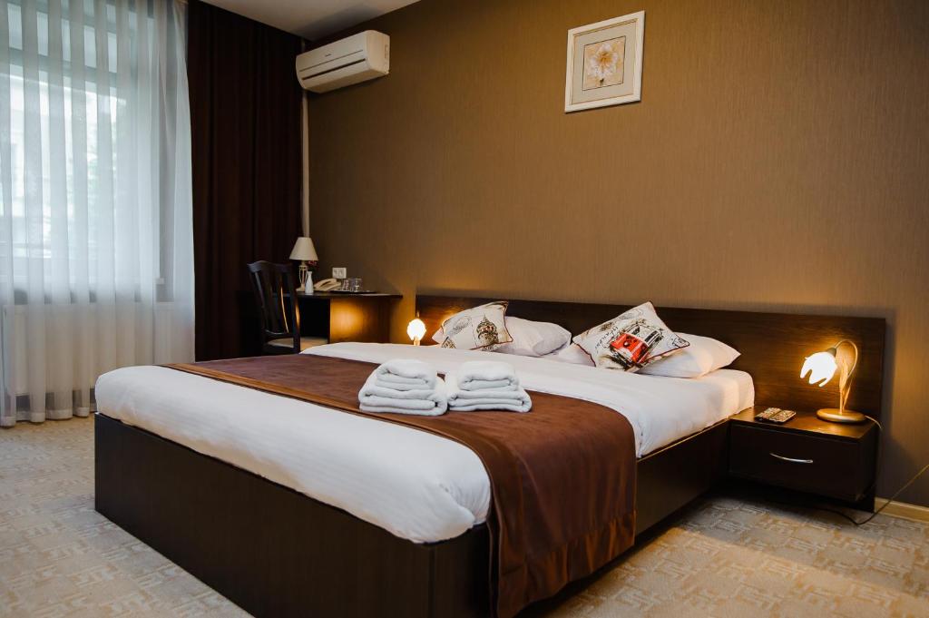 a hotel room with a large bed with towels on it at TipTop Hotel CITY CENTER in Chişinău