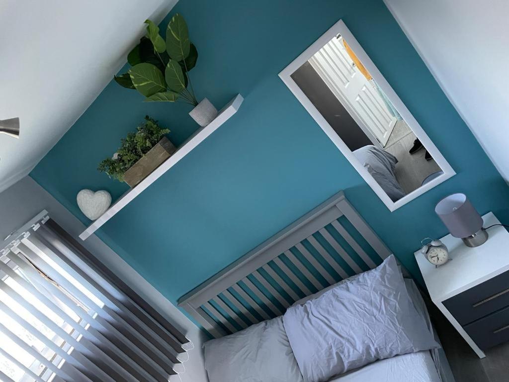 a blue bedroom with a bed and a mirror at 49 Cherry Park Chalet in Chapel Saint Leonards