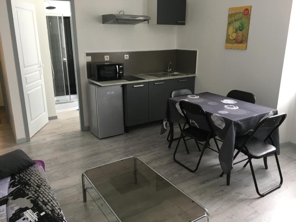 a living room with a table and chairs and a kitchen at F2 DU GATINAIS in Pithiviers