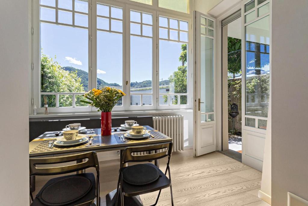 een eetkamer met een tafel en stoelen en grote ramen bij Garden Vista Lago in Como