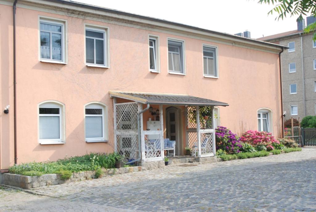uma casa cor-de-rosa com um portão e flores em Ferienwohnungen Stricker em Bad Muskau