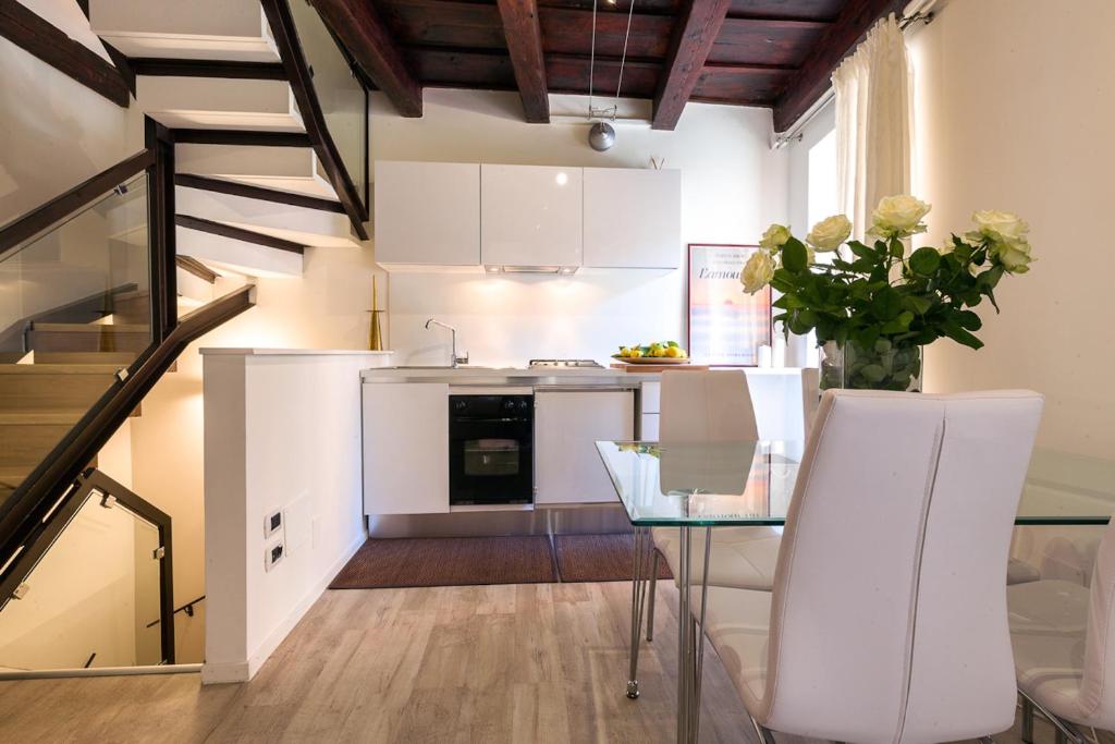 eine Küche mit weißen Schränken und einem Glastisch in der Unterkunft Corte Quaranta in Verona