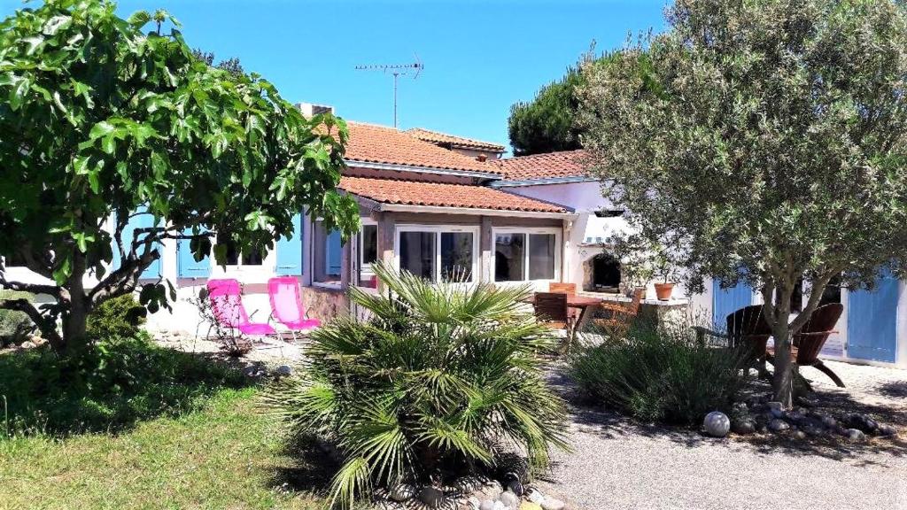 una casa con sillas rosas y árboles en el patio en Merlettes des Sables en Yves