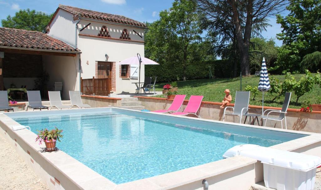 einen Pool mit Stühlen und ein Haus in der Unterkunft Le Pigeonnier de Lacalm GÎTE in Saint-Grégoire