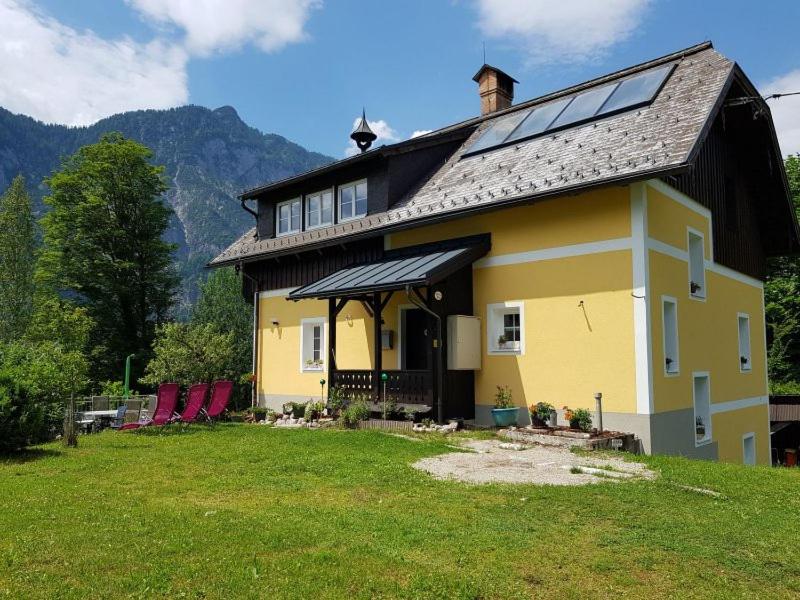 ein gelbes Haus mit einem Sonnendach auf einem Rasen in der Unterkunft Ferienhaus Kopriwa in Bad Goisern