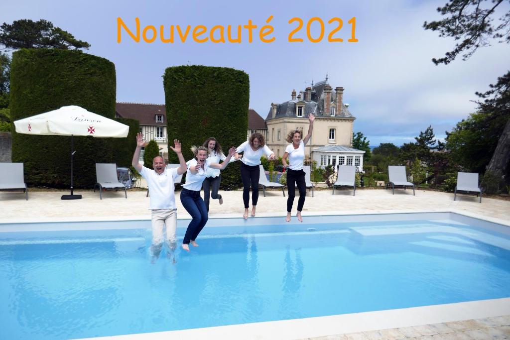 a group of people jumping in a swimming pool at Les Villas d'Arromanches, Teritoria in Arromanches-les-Bains