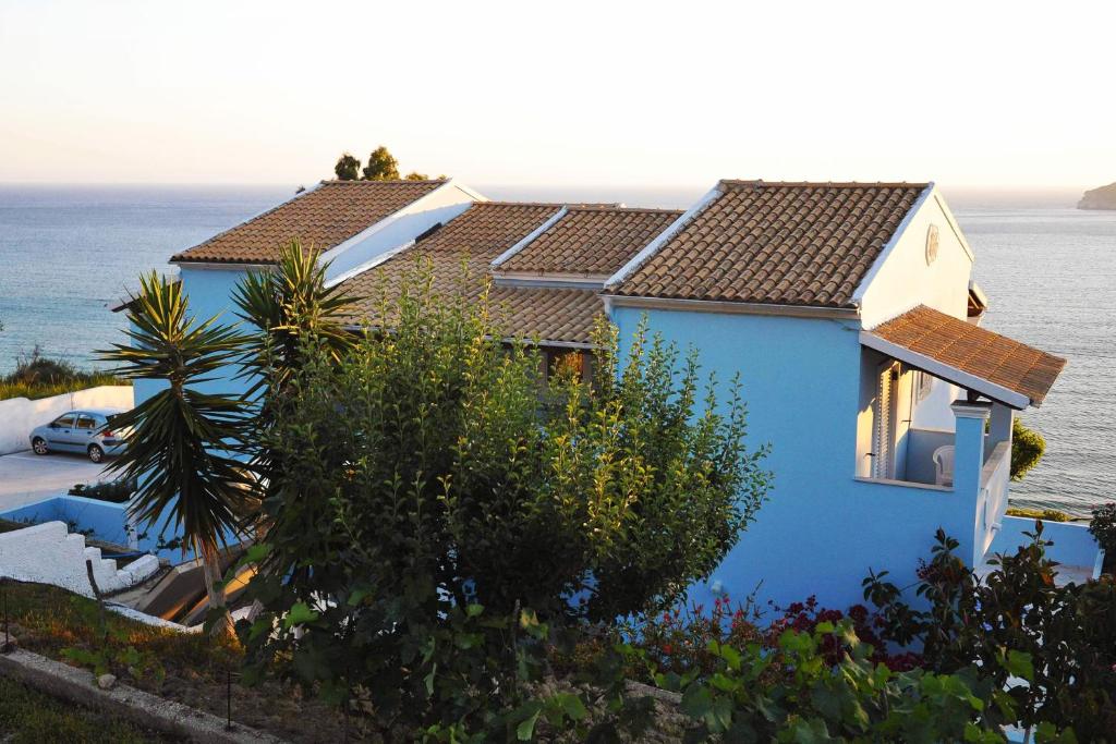 a blue house with the ocean in the background at theophilos blue cozy apartments in Agios Georgios Pagon