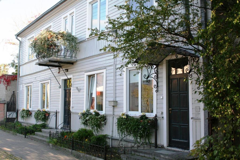 une maison blanche avec une porte noire dans une rue dans l'établissement KaunasInn, à Kaunas