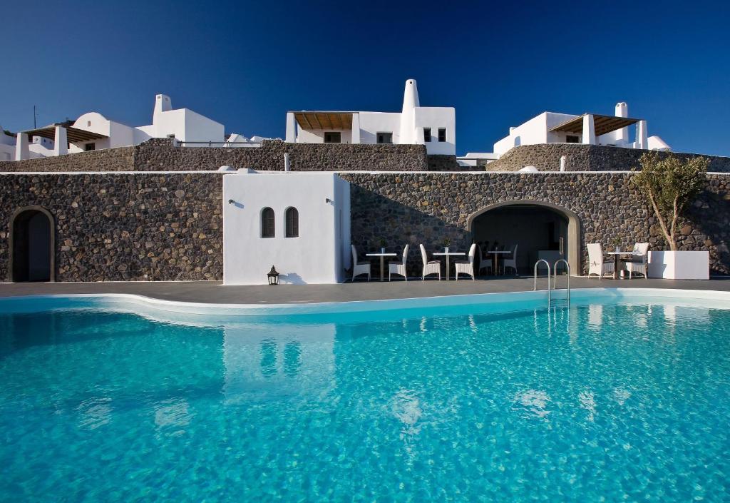 una piscina con acqua blu di fronte a un edificio di Carpe Diem Santorini a Pyrgos