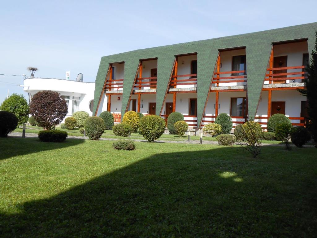 a building with a green lawn in front of it at Motel Sora in Sovata