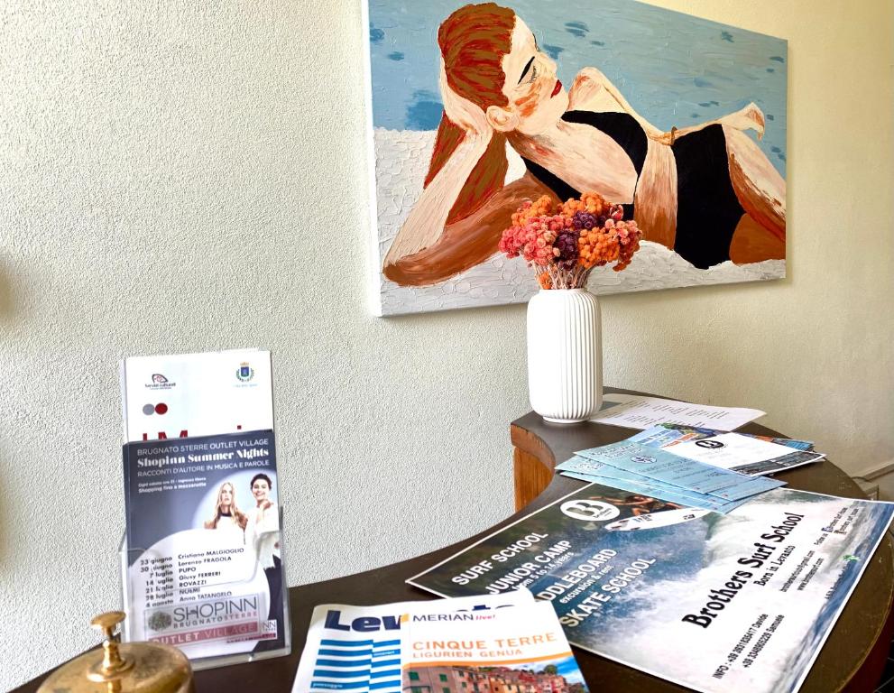 stół z wazonem kwiatów i obrazem w obiekcie Hotel Baia di Levanto w mieście Levanto
