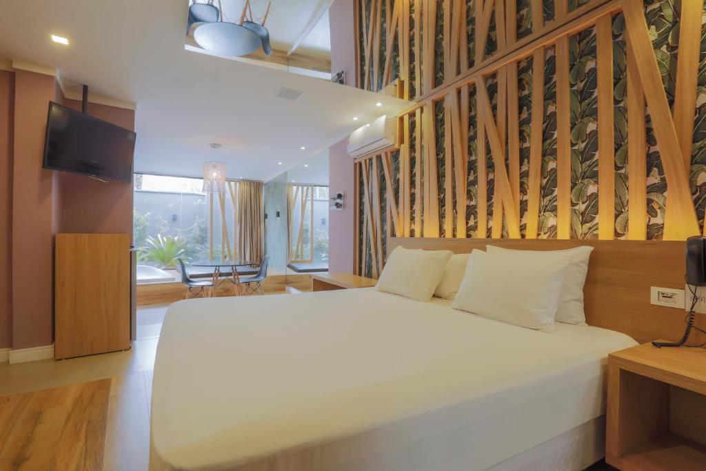um quarto com uma grande cama branca num quarto em Villages Motel by Drops em Lages