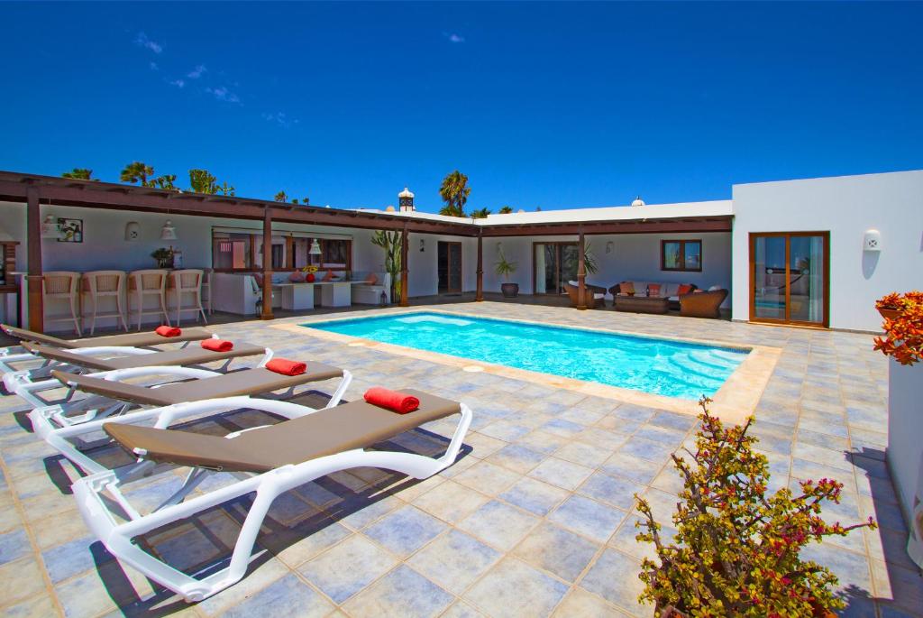 a swimming pool with lounge chairs and a house at Las Chimeneas in Playa Blanca