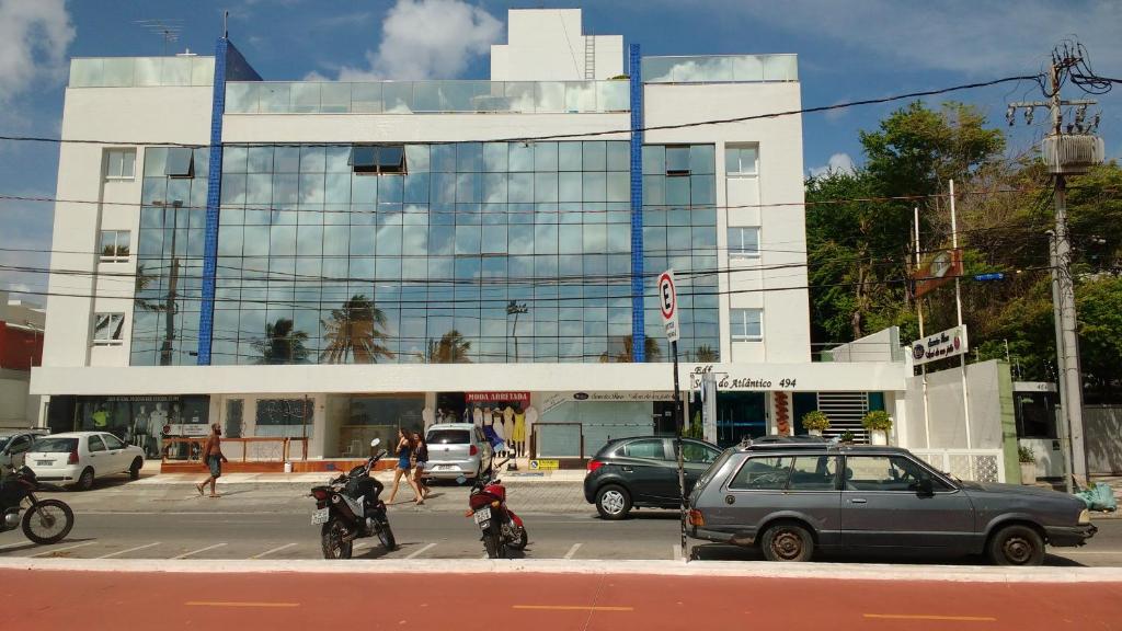 un bâtiment avec des voitures et des motos dans une rue de la ville dans l'établissement Sol e Mar Solar do Atlântico, à João Pessoa