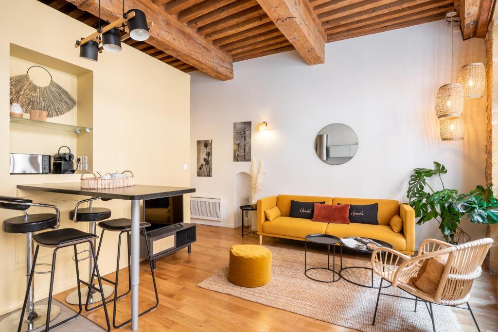 a living room with a yellow couch and a table at Honorê, Suite Saint Georges in Lyon
