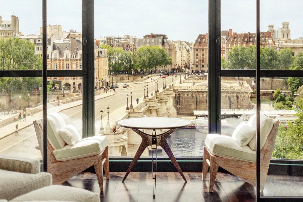 a room with a table and chairs and a view of a city at Cheval Blanc Paris & Dior Spa Cheval Blanc Paris in Paris