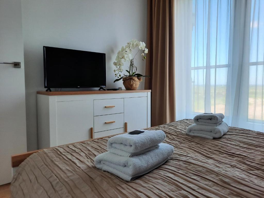 a bedroom with a bed with towels on it at Aqua Apartments Sunset in Reda