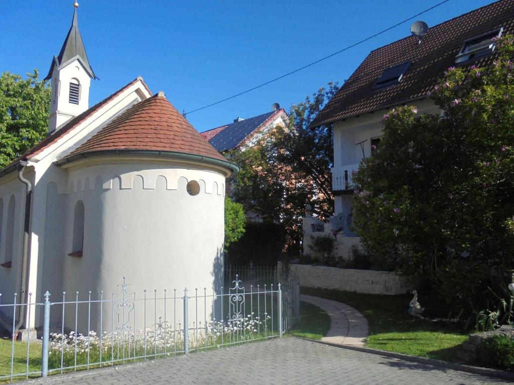 uma cerca branca em frente a uma igreja em Ferienwohnung im Barockwinkel em Neuburg an der Kammel