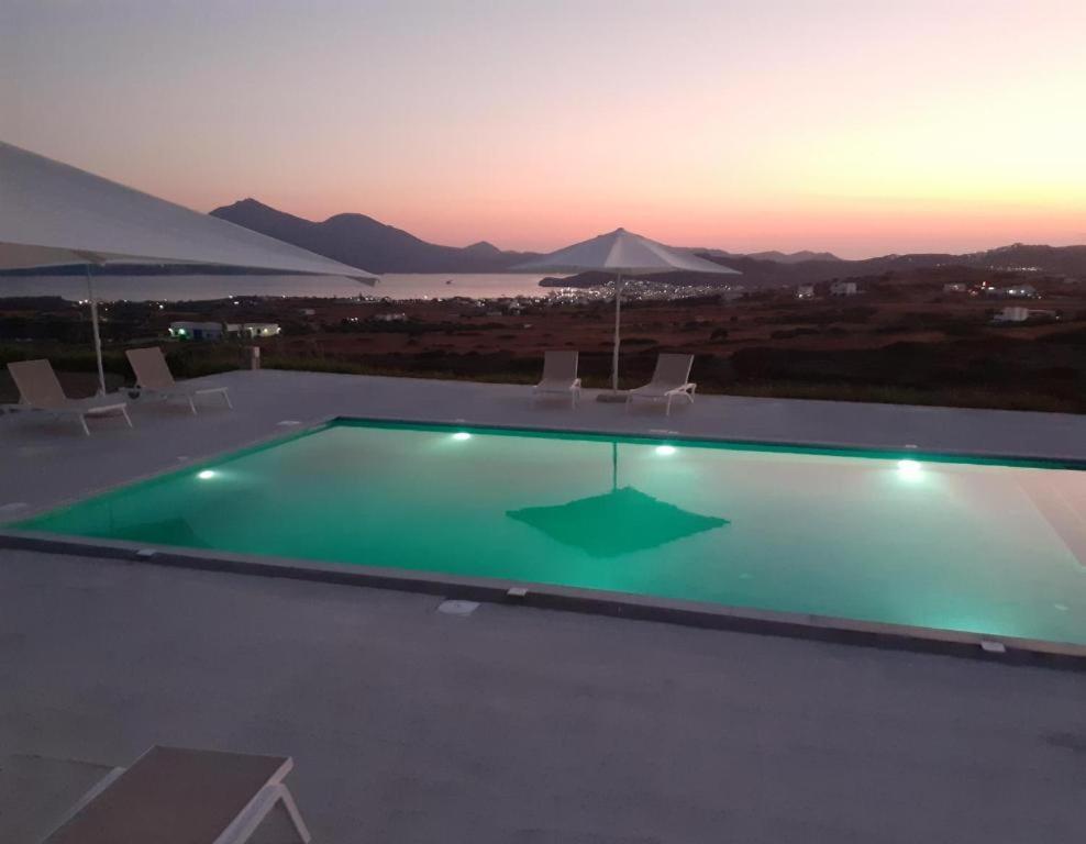 a swimming pool with a sunset in the background at elena in Adamantas