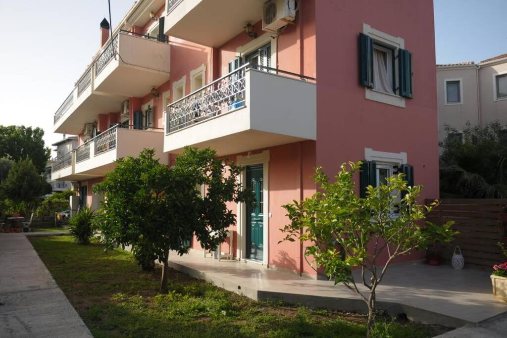 a pink apartment building with a balcony and trees at lividio apartment in Lefkada