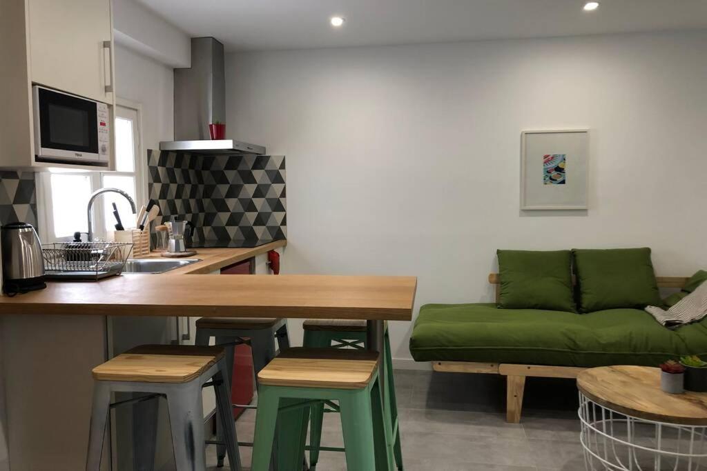 Il comprend un salon avec un canapé vert et une cuisine. dans l'établissement M3 Terrace. Cool apartment 15 min center by metro, à Esplugues de Llobregat