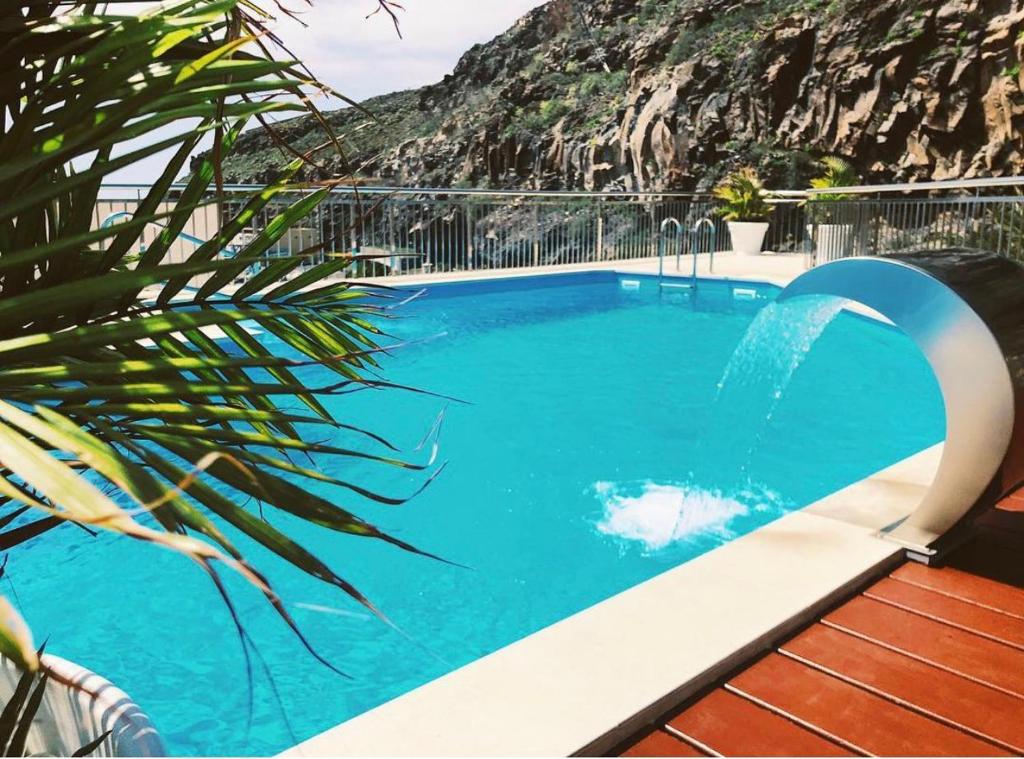 a large blue swimming pool with a waterfall at Apartamentos Tapahuga in Playa de Santiago