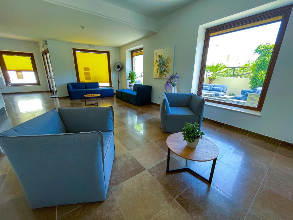 a living room with blue chairs and a table at Hotel Sikania in San Vito lo Capo