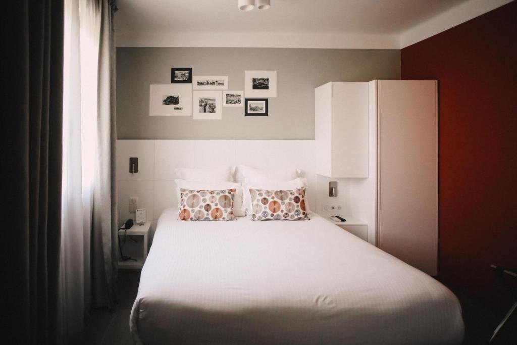 a bedroom with a white bed with two pillows at Best Western Plus La Corniche in Toulon