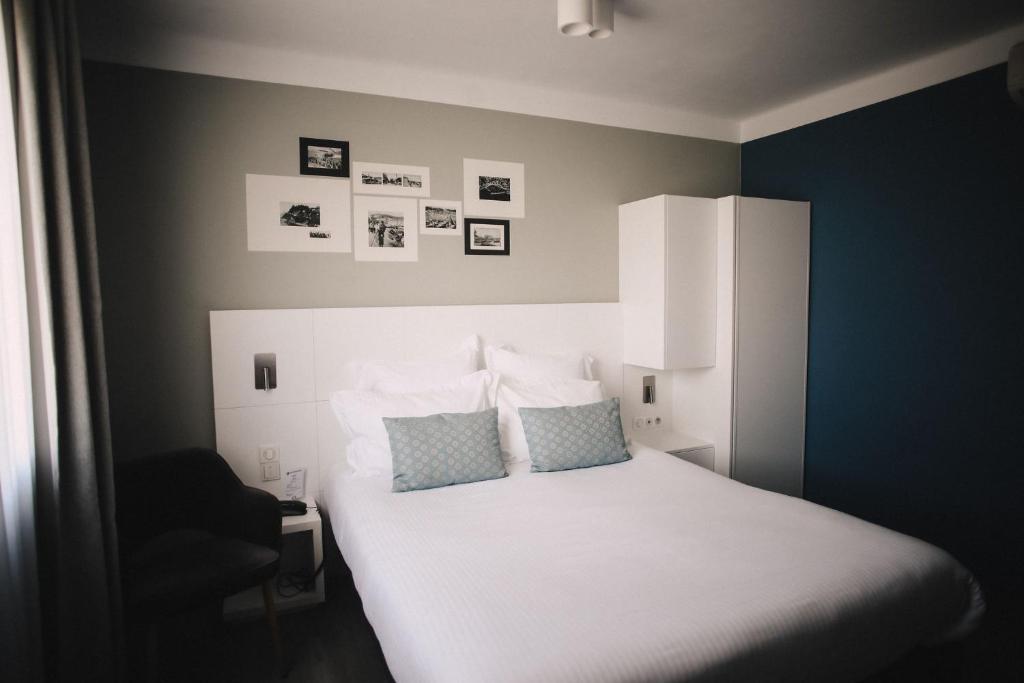 a bedroom with a white bed and a chair at Best Western Plus La Corniche in Toulon
