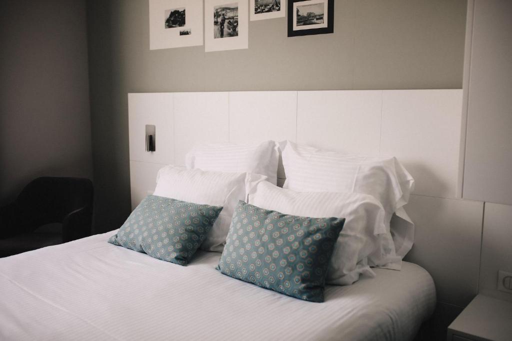 a bed with white sheets and blue pillows at Best Western Plus La Corniche in Toulon