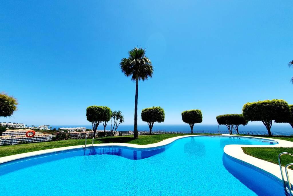 einen großen Pool mit Palmen und dem Meer in der Unterkunft Alcores Seaviews in Sitio de Calahonda