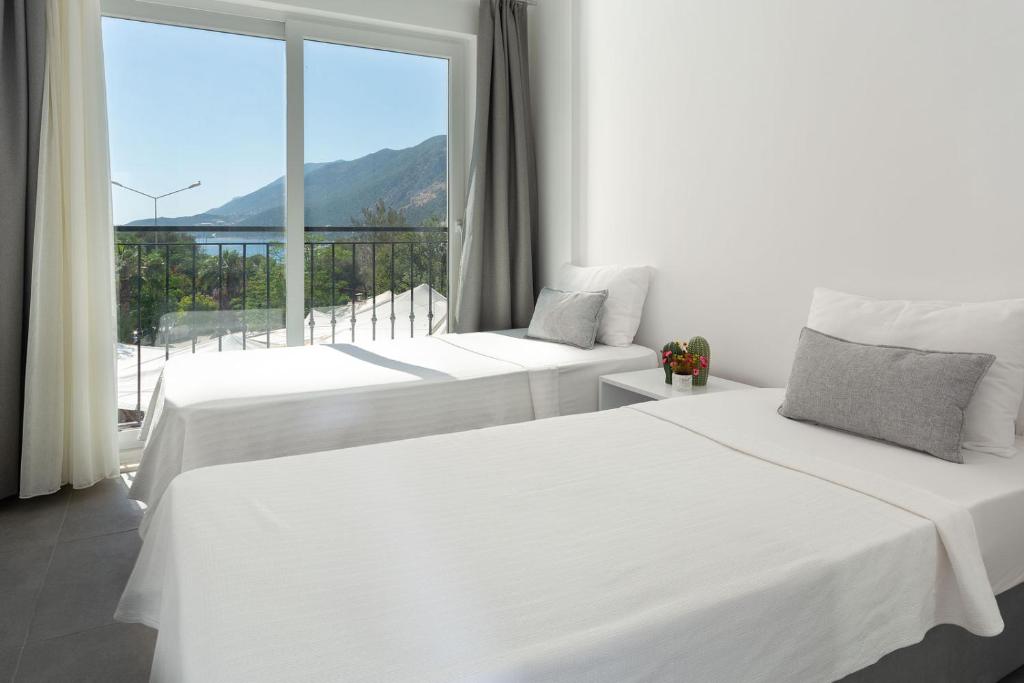 two beds in a room with a large window at La Moda Aparts in Kaş