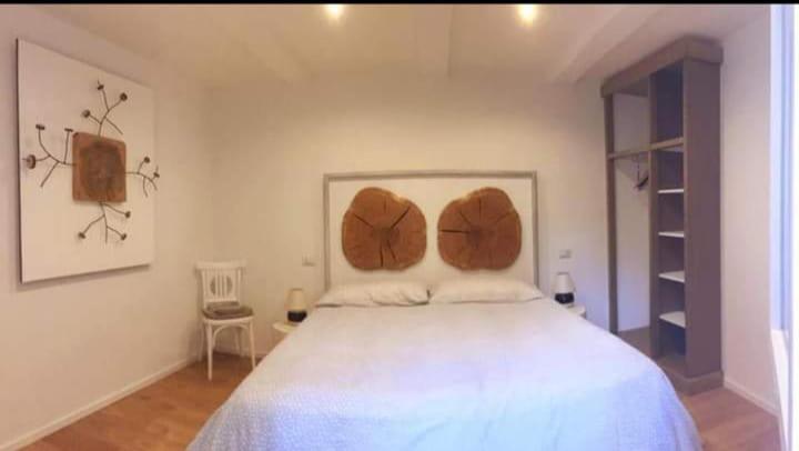 Schlafzimmer mit einem großen weißen Bett mit Kopfteilen aus Holz in der Unterkunft Miniappartamento Larice in Torgiano