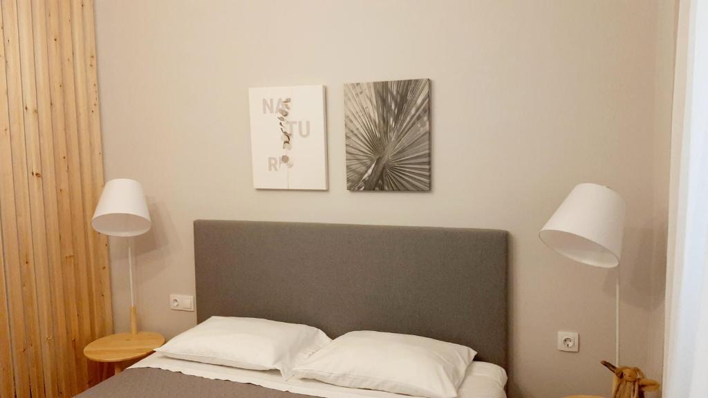 un letto con due cuscini bianchi e due quadri sul muro di Habitat Nafplio bnb - Open space studio a Nauplia