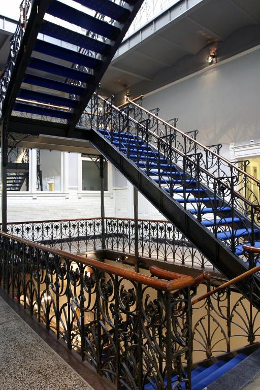 a staircase with blue stairs in a building with a bench at Hotel New York by WestCord in Rotterdam