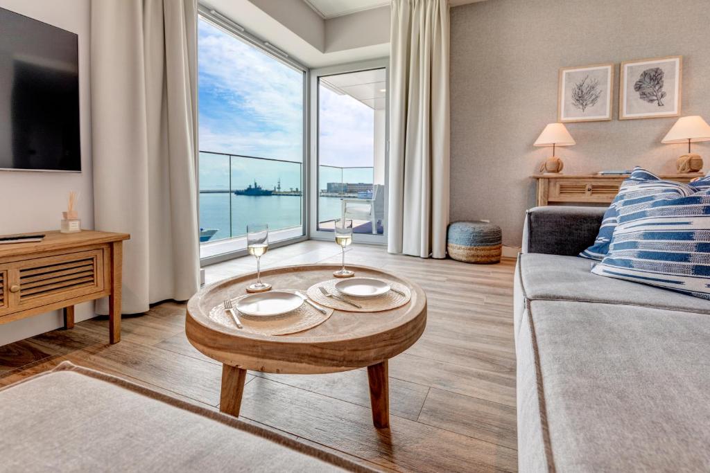 ein Wohnzimmer mit einem Tisch und einem großen Fenster in der Unterkunft Yacht Park Marina by AmberBlue in Gdynia
