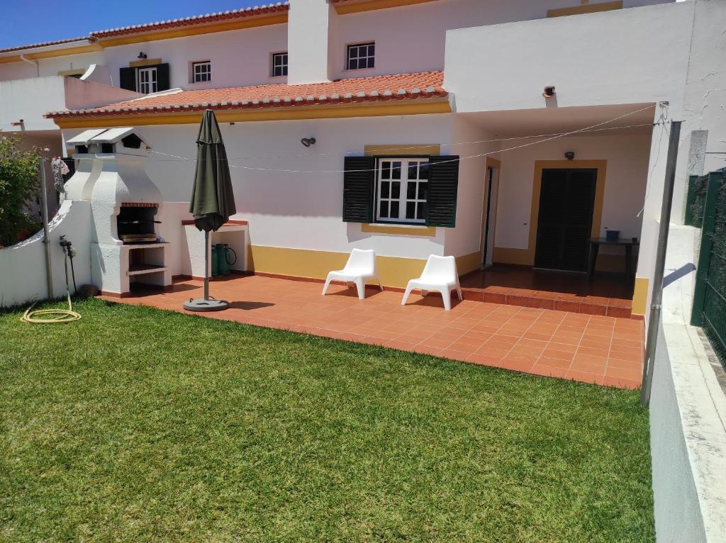 - une terrasse avec 2 chaises et un parasol en face d'une maison dans l'établissement Ergobeach House, à Almograve