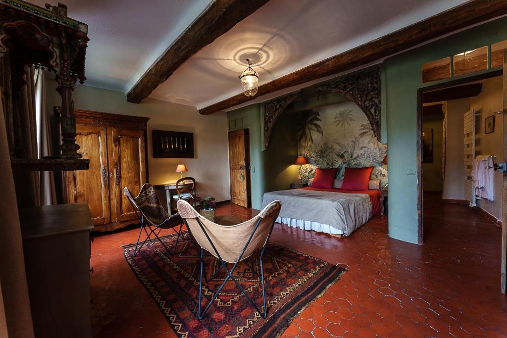 a bedroom with a bed and two chairs in it at La Bouscatière in Moustiers-Sainte-Marie