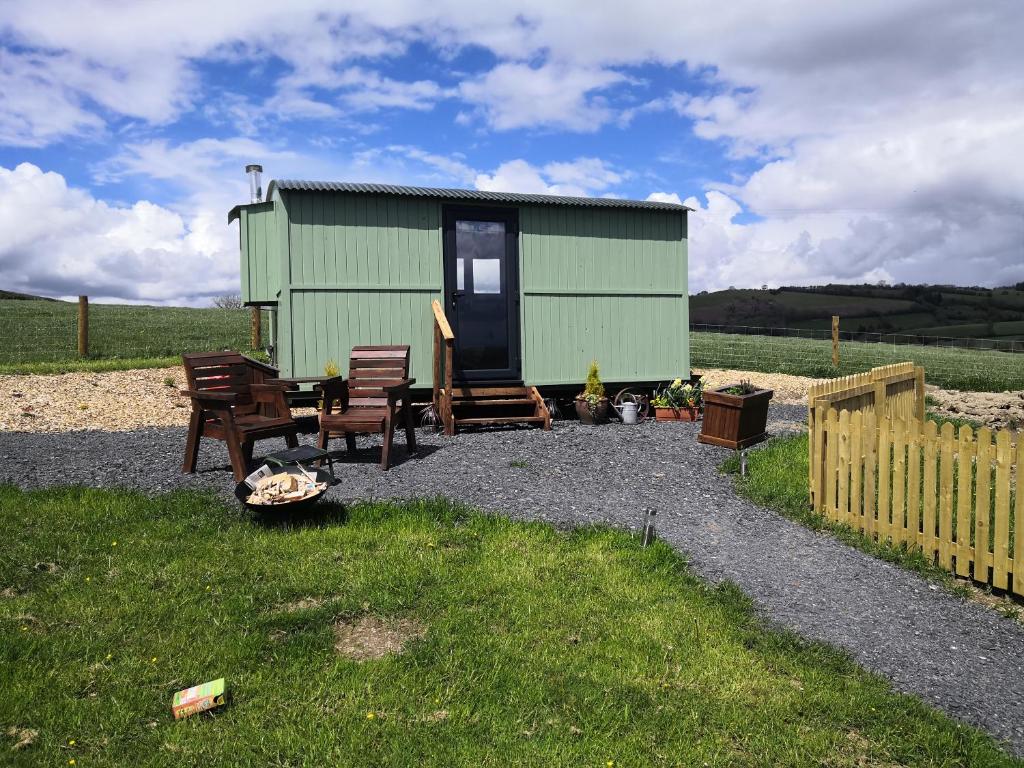 a green shed with chairs and a table and a fence at Y Cwtch in Trefeglwys